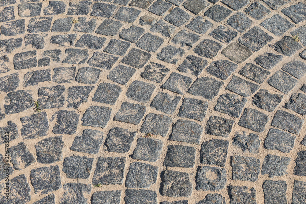 Cobbled road close-up. Pedestrian paving in street. Paved, detail. Brown texture of a paving stone track on sand. Cobbled road close-up. Pedestrian paving in street. Paved, detail. Brown texture of a paving stone track on sand.