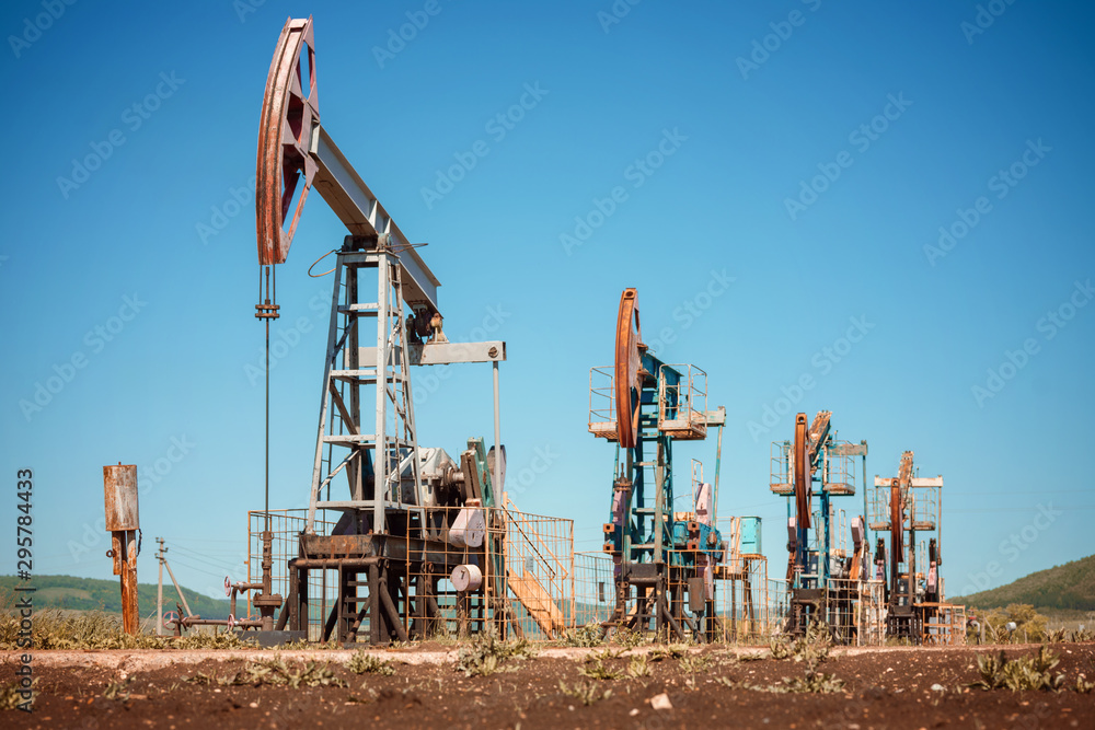Oil pump jack rocking with pipeline in the background. Rocking machines for power generation. Extraction of oil