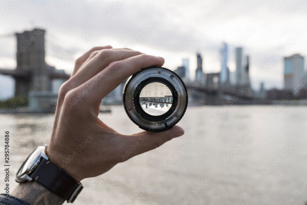 Fototapeta Ręka trzyma obiektyw przeciwko panoramę Nowego Jorku