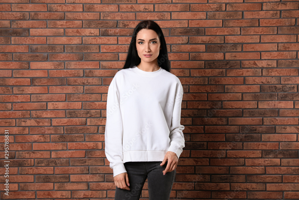 Portrait of young woman in sweater at brick wall. Mock up for design Portrait of young woman in sweater at brick wall. Mock up for design