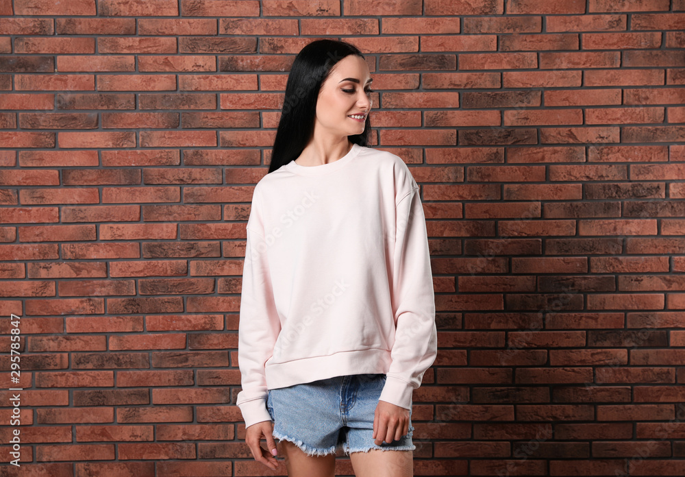 Portrait of young woman in sweater at brick wall. Mock up for design