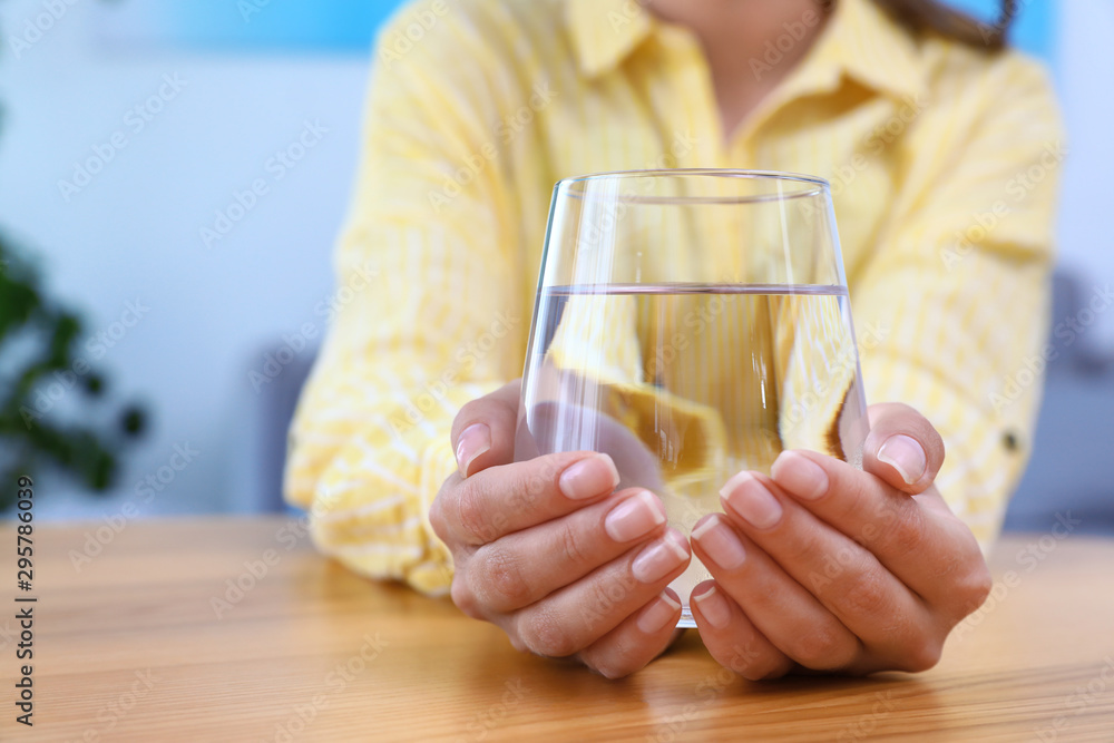 Woman holding glass of water at wooden table, closeup with space for text. Refreshing drink Woman holding glass of water at wooden table, closeup with space for text. Refreshing drink