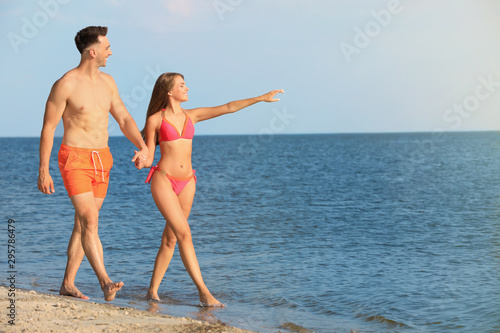 Young woman in bikini spending time with her boyfriend on beach. Lovely couple © New Africa