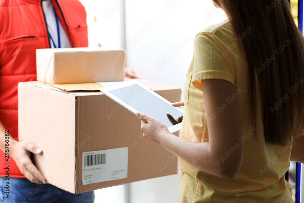 Woman using app to confirm delivery of parcel from courier on doorstep, closeup Woman using app to confirm delivery of parcel from courier on doorstep, closeup