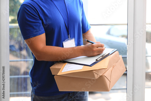 Young courier delivering parcels on doorstep, closeup