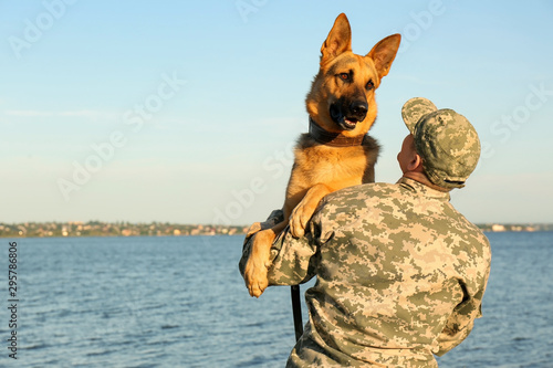 Man in military uniform with German shepherd dog outdoors photo