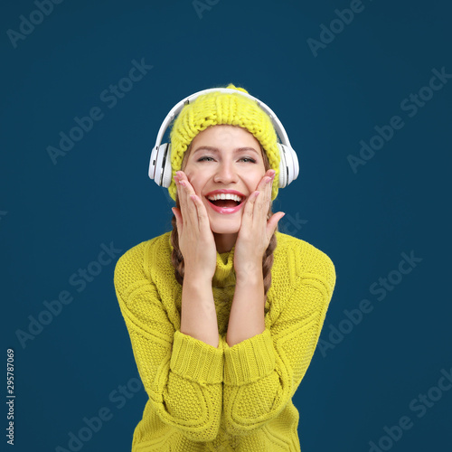 Young woman listening to music with headphones on dark blue background