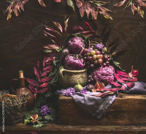 Still life with purple fruits and vegetables on wooden table with autumn leaves. Copy space for your design