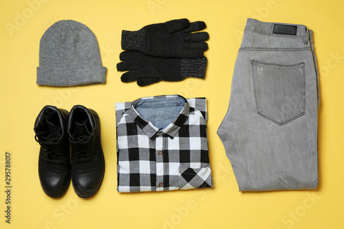 Flat lay composition with winter clothes and boots on yellow background
