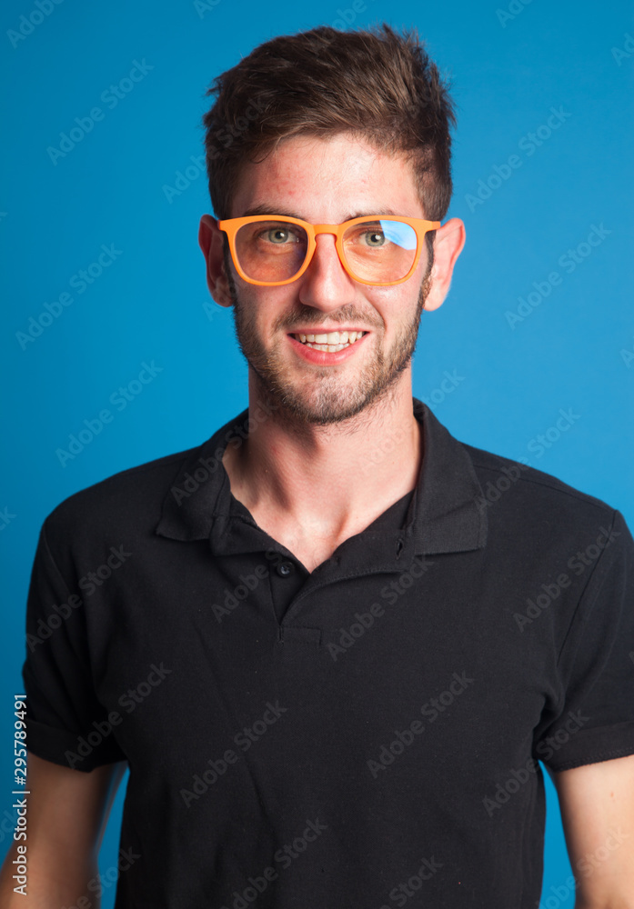 Chico joven sobre fondo azul que lleva unas gafas o lentes para poder ver bien Chico joven sobre fondo azul que lleva unas gafas o lentes para poder ver bien