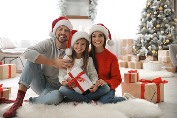 Portrait of happy family with Christmas gifts on floor at home