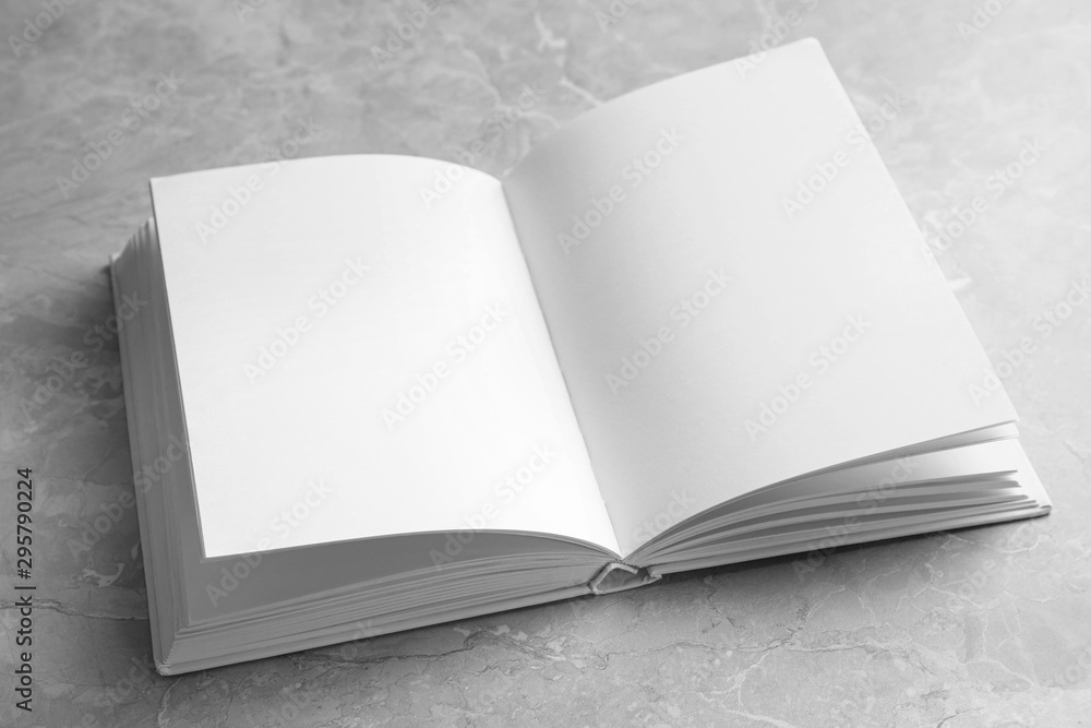 Open book with blank pages on light grey marble background. Mock up for design Open book with blank pages on light grey marble background. Mock up for design