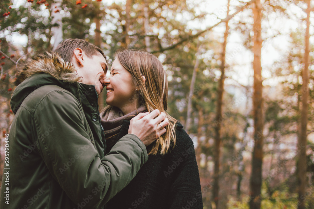 Fototapeta premium Happy young couple in love friends dressed in casual style kissing in nature park forest in cold season, family advenure travel
