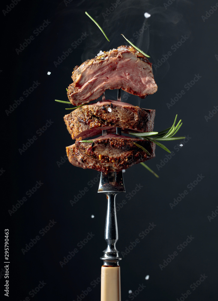 Fototapeta Grilled ribeye beef steak with rosemary on a black background.