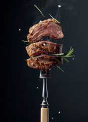 Grilled ribeye beef steak with rosemary on a black background.