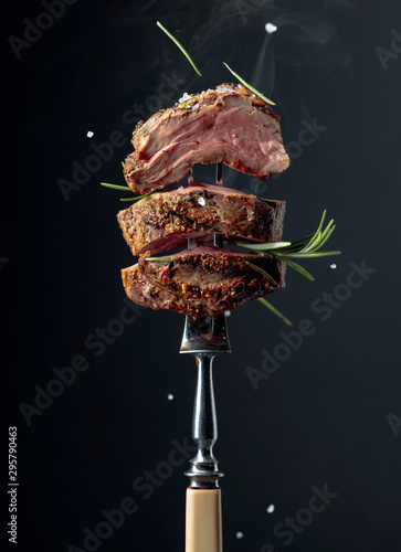 Fototapeta Grilled ribeye beef steak with rosemary on a black background.