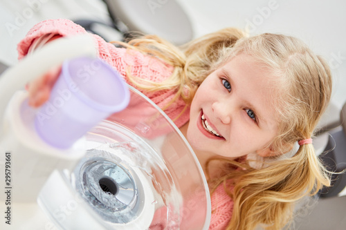 Kind beim Zahnarzt mit einem Plastikbecher Wasser photo