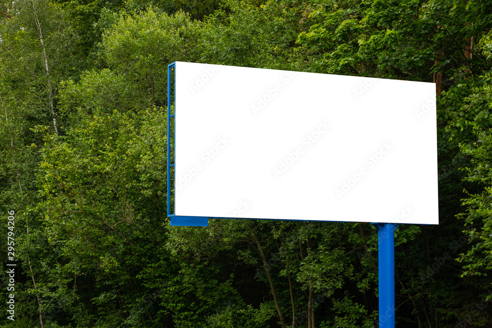 Close-up white blank billboard against forest along road