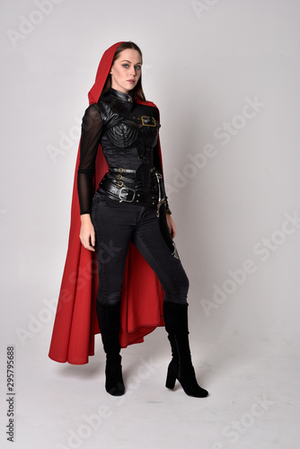 Fotótapéta full length portrait of a pretty brunette woman wearing black leather fantasy costume with long red superhero cape