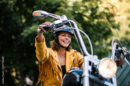 Foto Cheerful senior woman traveller with motorbike in town.