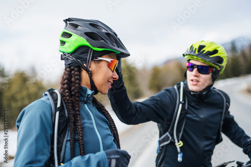 Two mountain bikers riding on road outdoors in winter.
