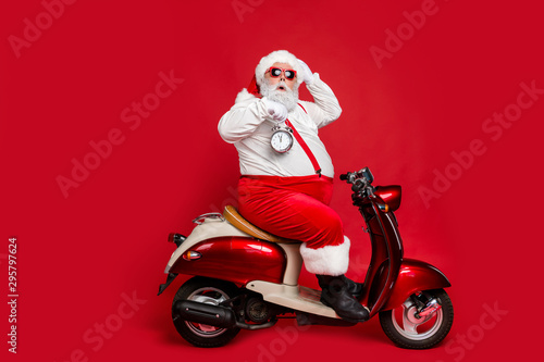 Profile side view of nice bearded worried funky Santa sitting on moped holding in hand clock countdown winter discount sale isolated on bright vivid shine vibrant red color background