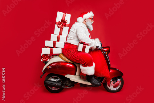 Profile side view of nice bearded focused funky fat Santa riding moped pile stack winter fairy purchases isolated on bright vivid shine vibrant red color background