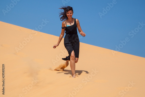 beautiful girl in the desert runs barefoot on the top of the hill in the sand