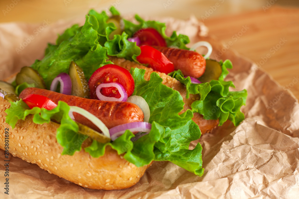 two juicy Hot dog with lettuce, onion, cucumber and sauce on wooden background. Hot dog with tomatoes, mustard sauce two juicy Hot dog with lettuce, onion, cucumber and sauce on wooden background. Hot dog with tomatoes, mustard sauce