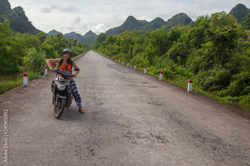 girl biker riding a scooter in the mountains of Vietnam, Woman in blue helmet riding scooter motorbike, Female traveler riding a motorcycle scooter in Vietnam © evgenii