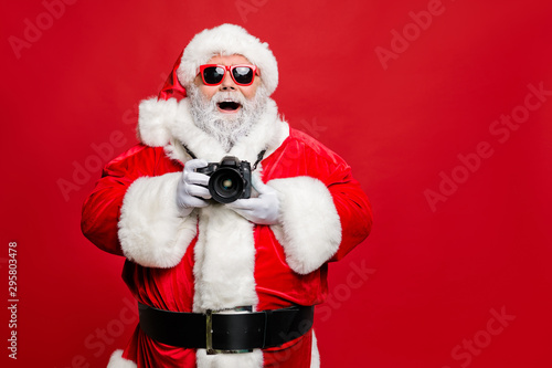 Portrait of excited enthusiastic santa claus in eyewear eyeglasses have voyage take photo wear stylish costume cap hat belt isolated over red background