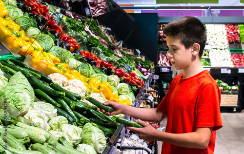 Bilde på lerret Child selecting vegetables on shelf in supermarket.