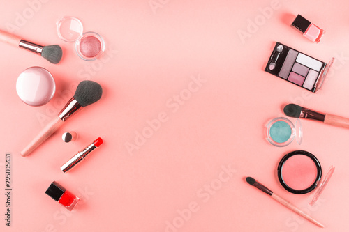 Make up products and brushes on pink background. Beauty items colorful fashion flat lay