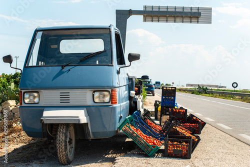 Fototapeta Naklejka Na Ścianę i Meble -  Small italian apo truck with tomatoes. Farmer sale tomatoes on the street in Italy.