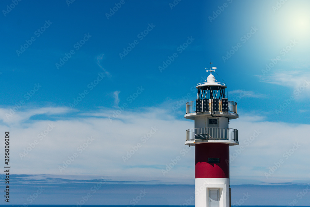 maritime lighthouse on cliff with blue sea in the background