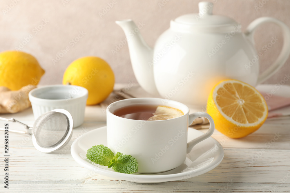 Cup of tea with lemon, mint, strainer, ginger and teapot on wooden background, space for text Cup of tea with lemon, mint, strainer, ginger and teapot on wooden background, space for text