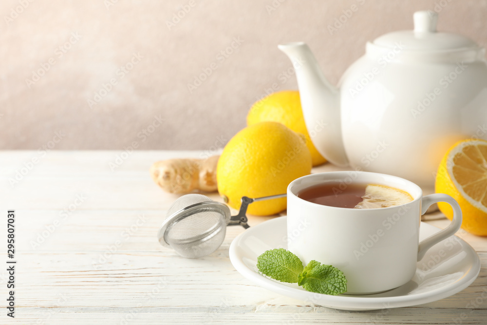 Cup of tea with lemon, mint, strainer, ginger and teapot on wooden background, copy space Cup of tea with lemon, mint, strainer, ginger and teapot on wooden background, copy space