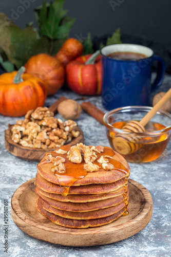 Delicious homemade pumpkin pancakes served with walnuts and honey, autumn decoration, vertical