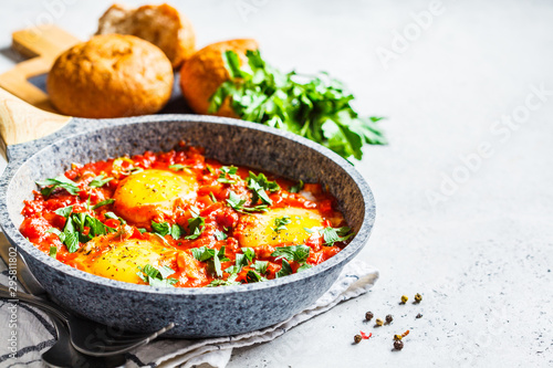 Traditional shakshuka in  pan. Fried eggs in tomato sauce with herbs.