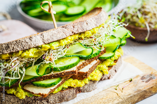 Big veggie sandwich with tofu, vegetables, sprouts and guacamole. Healthy vegan food concept.