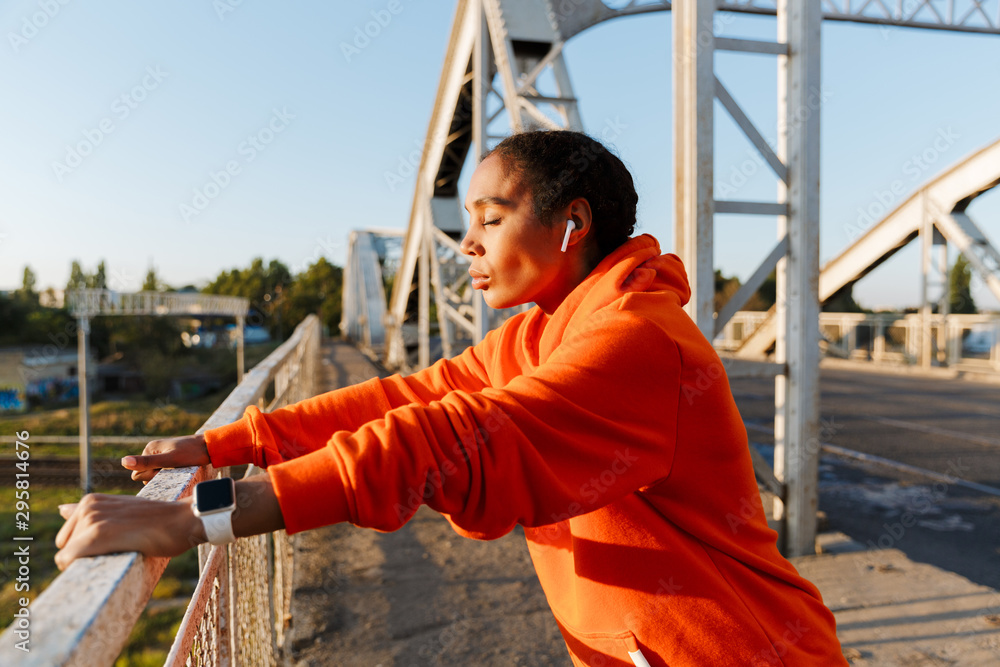 Obraz premium Photo of african american woman using earpods while leaning on railing