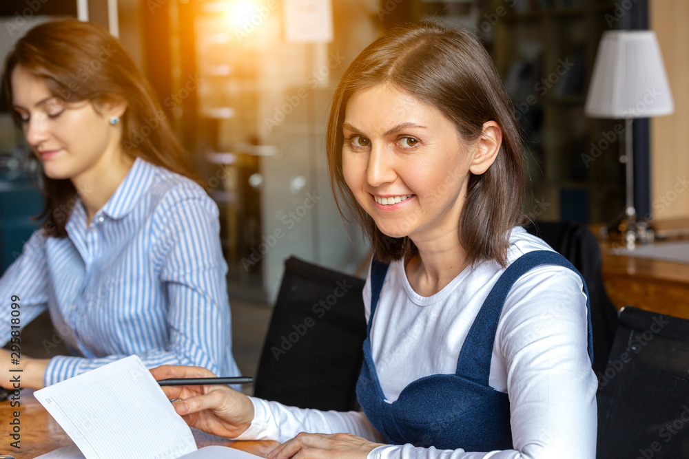the girl works in a successful young company in their office. Portrait of a young smiling girl. Concept of successful business and work the girl works in a successful young company in their office. Portrait of a young smiling girl. Concept of successful business and work