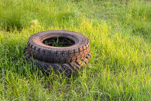 Car rubber tires thrown into a stack on green grass. Nono-ecological technogenic material in nature. Environmental pollution.