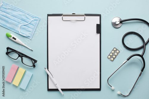 Overhead view healthcare accessories near clipboard with plank paper and spectacles on background