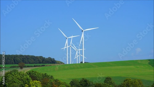 Windkraftanlage mit vielen Windrädern gestaffelt vor blauem Himmel – Wind turbine with many windmills staggered in front of blue sky