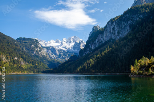 Fototapeta Naklejka Na Ścianę i Meble -  Famous Lake Gosau and Gosaukamm with Mount Dachstein. The sun is about to hide behind the high peaks while autumn is about to settle in with all the vibrant colors around the lake and hills.