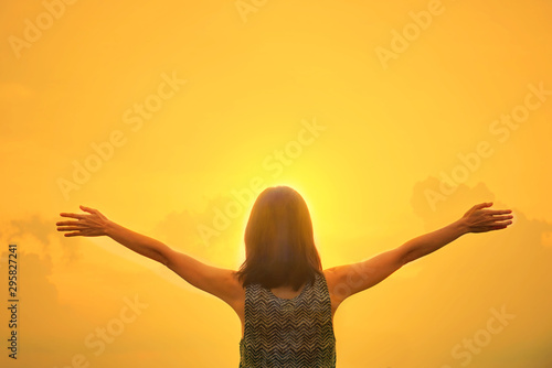 Silhouette happy woman stand alone and open arms with background sunset sky.