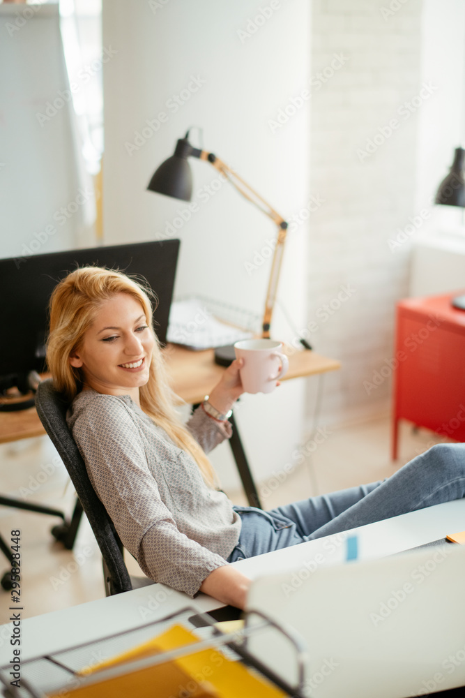 young businesswoman drinking coffee and using lap top in the office young businesswoman drinking coffee and using lap top in the office