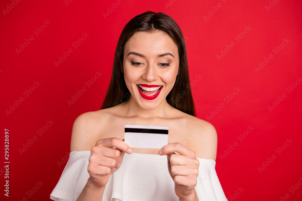 Close up photo of pretty youth holding plastic card screaming shouting dressed off-shoulders isolated over red background Close up photo of pretty youth holding plastic card screaming shouting dressed off-shoulders isolated over red background
