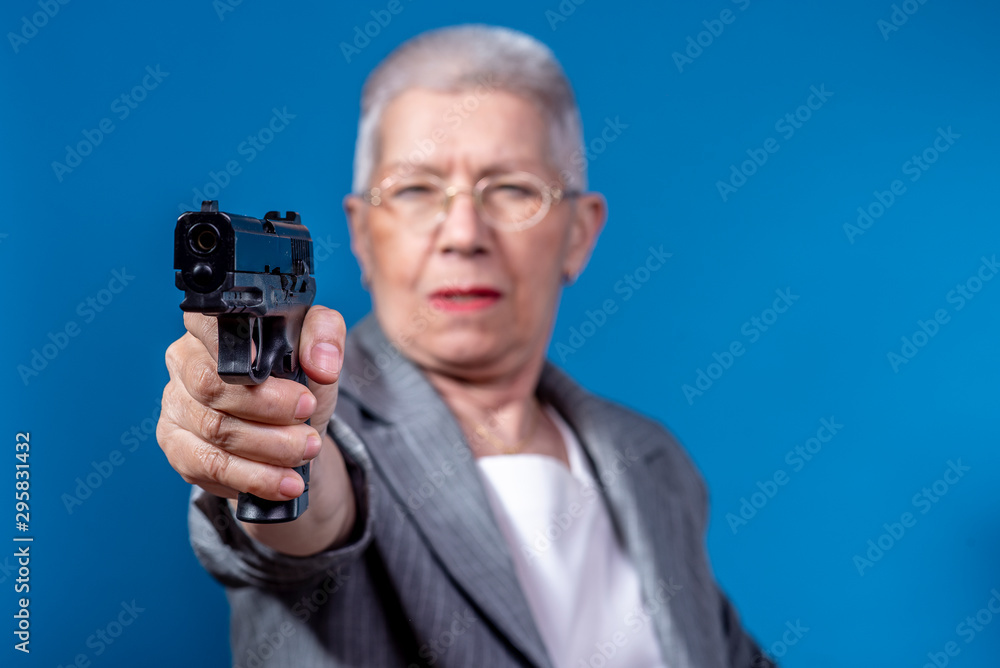 Old business lady aiming with her weapon, looking angry Old business lady aiming with her weapon, looking angry